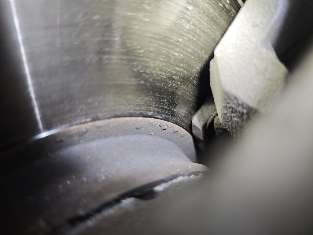 Blick auf eine Bremsscheibe und einen fast vollständig abgenutzten Bremsbelag im Bremssattel