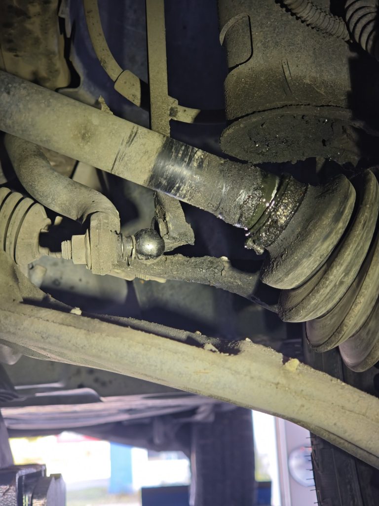 Blick von unten auf die Vorderachse eines VW Widder mit gebrochener Koppelstange am Kugelgelenk und loser Antriebswellenmanschette